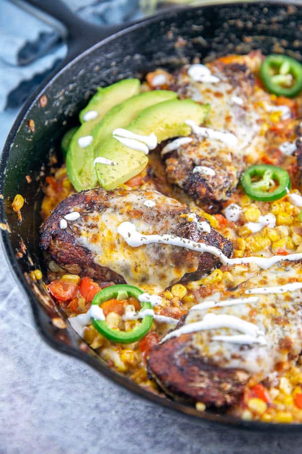 cast iron chicken skillet dinner with avocados and drizzled sour cream