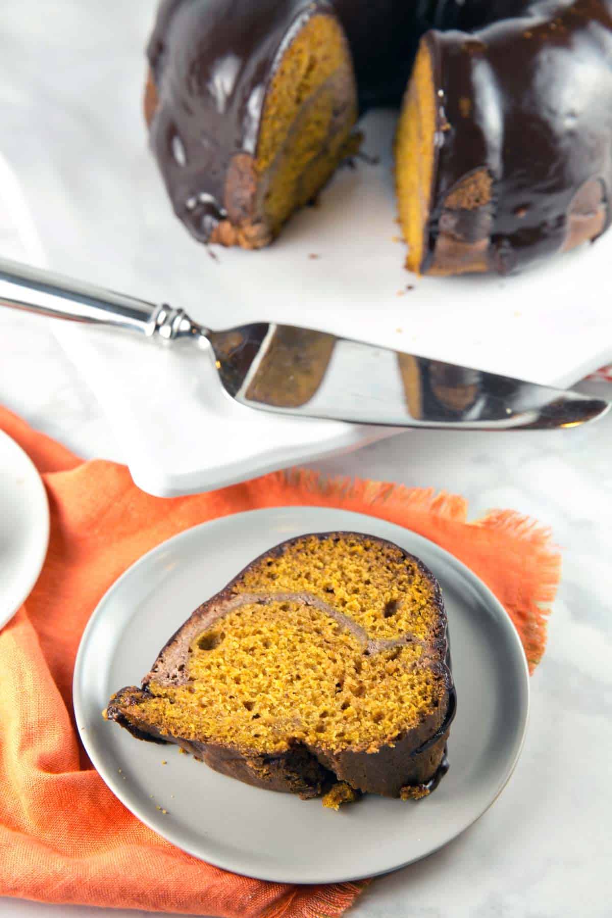 one slice of cream cheese swirl pumpkin bundt cake on a gray plate.