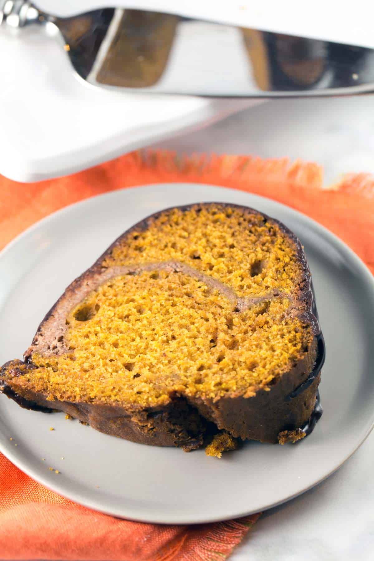 slice of cream cheese swirl pumpkin bundt cake on an orange cloth placemat.