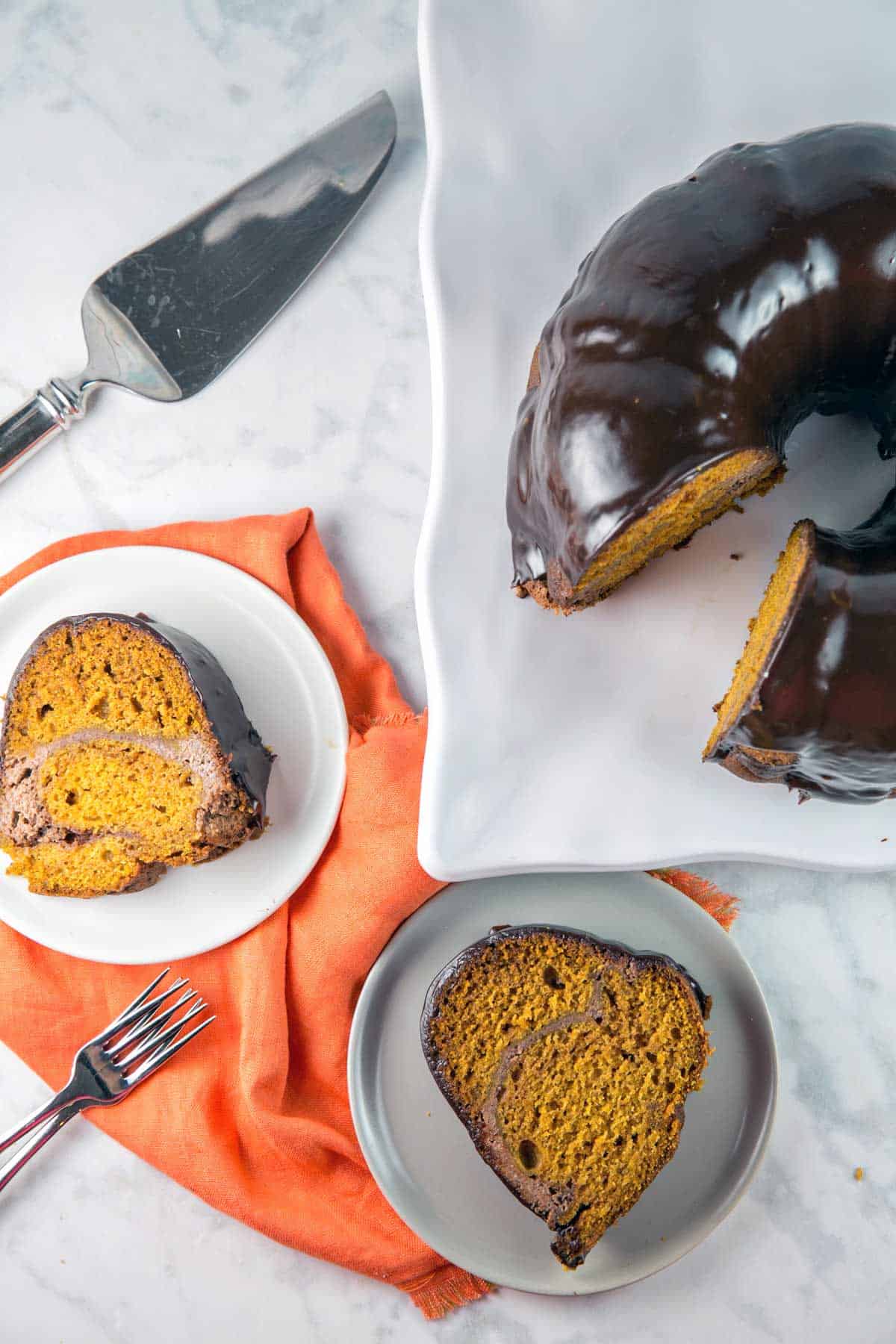 two slices of pumpkin bundt cake next to a chocolate covered cake.