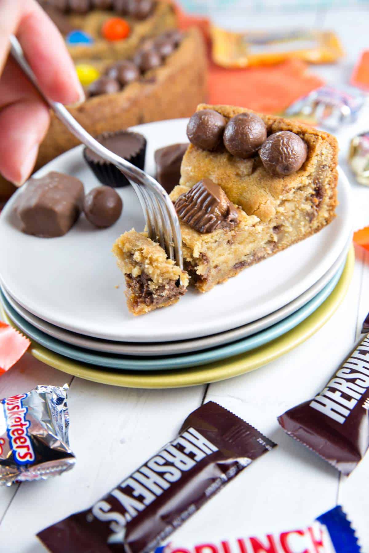 hand with a fork digging into a slice of a halloween candy cookie cake.