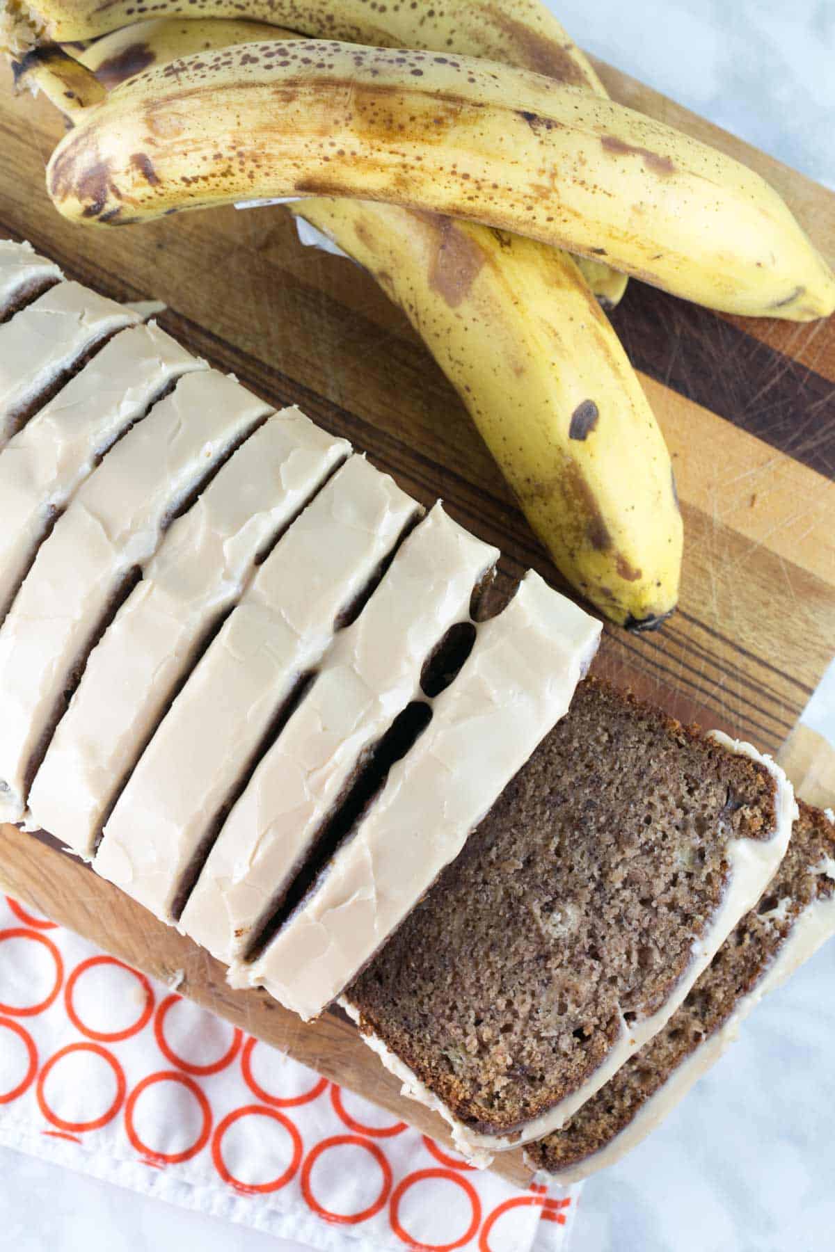 a loaf of maple banana bread sliced on a wood cutting board