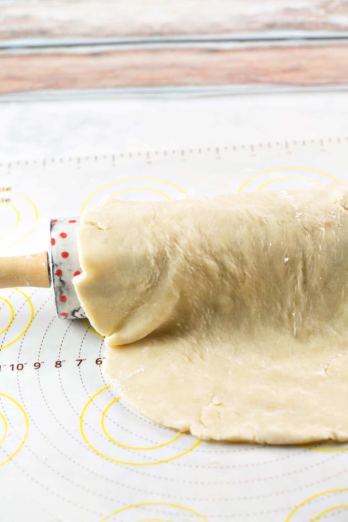 sheet of pie crust dough draped over a decorative rolling pin.