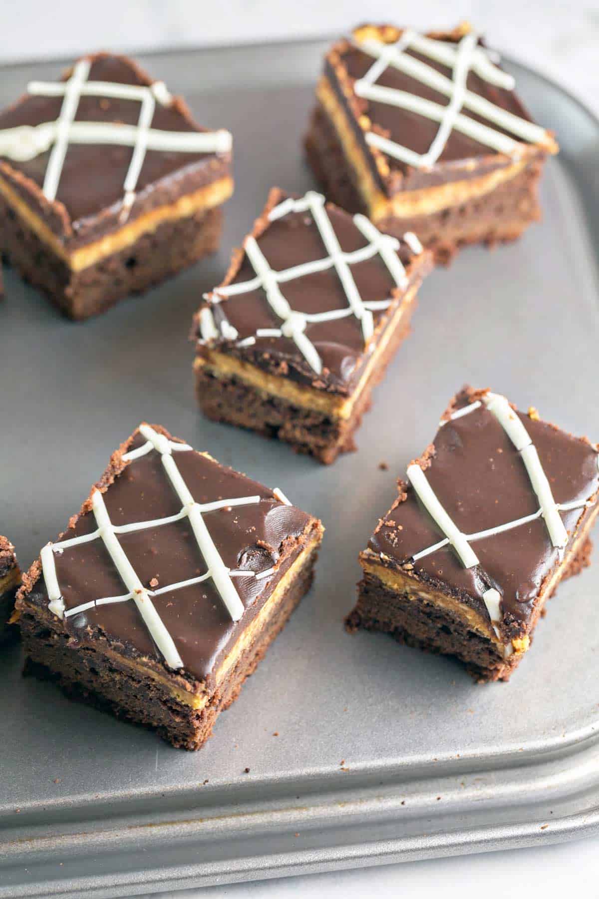 five pumpkin cheesecake brownies on a baking sheet.