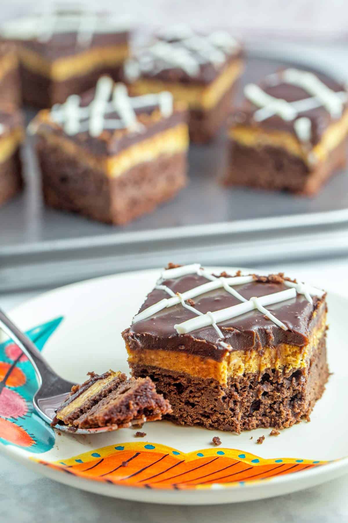 one pumpkin cheesecake brownie on a plate with one bite removed.