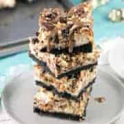 Snickers Cheesecake Bars: Handheld cheesecake bars full of chopped Snickers, a crunchy chocolate and peanut topping, and a drizzle of melted chocolate and caramel. #bunsenburnerbakery #cheesecake #Snickers #cheesecakebars