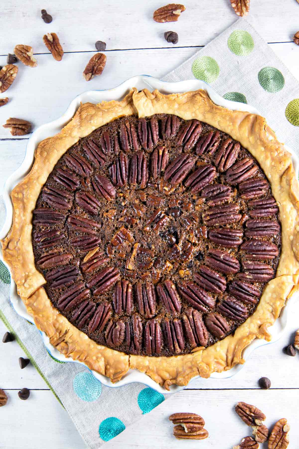 overhead view of a whole chocolate bourbon pecan pie with pecans arranged decoratively on the surface.