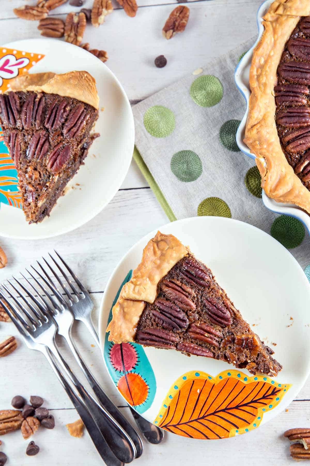 two slices of chocolate bourbon pecan pie on fall themed dessert plates.