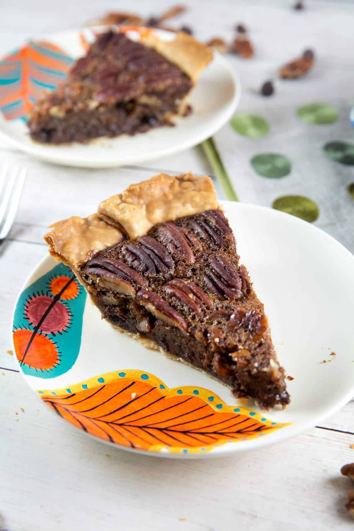 two slices of chocolate bourbon pecan pie on fall plates.