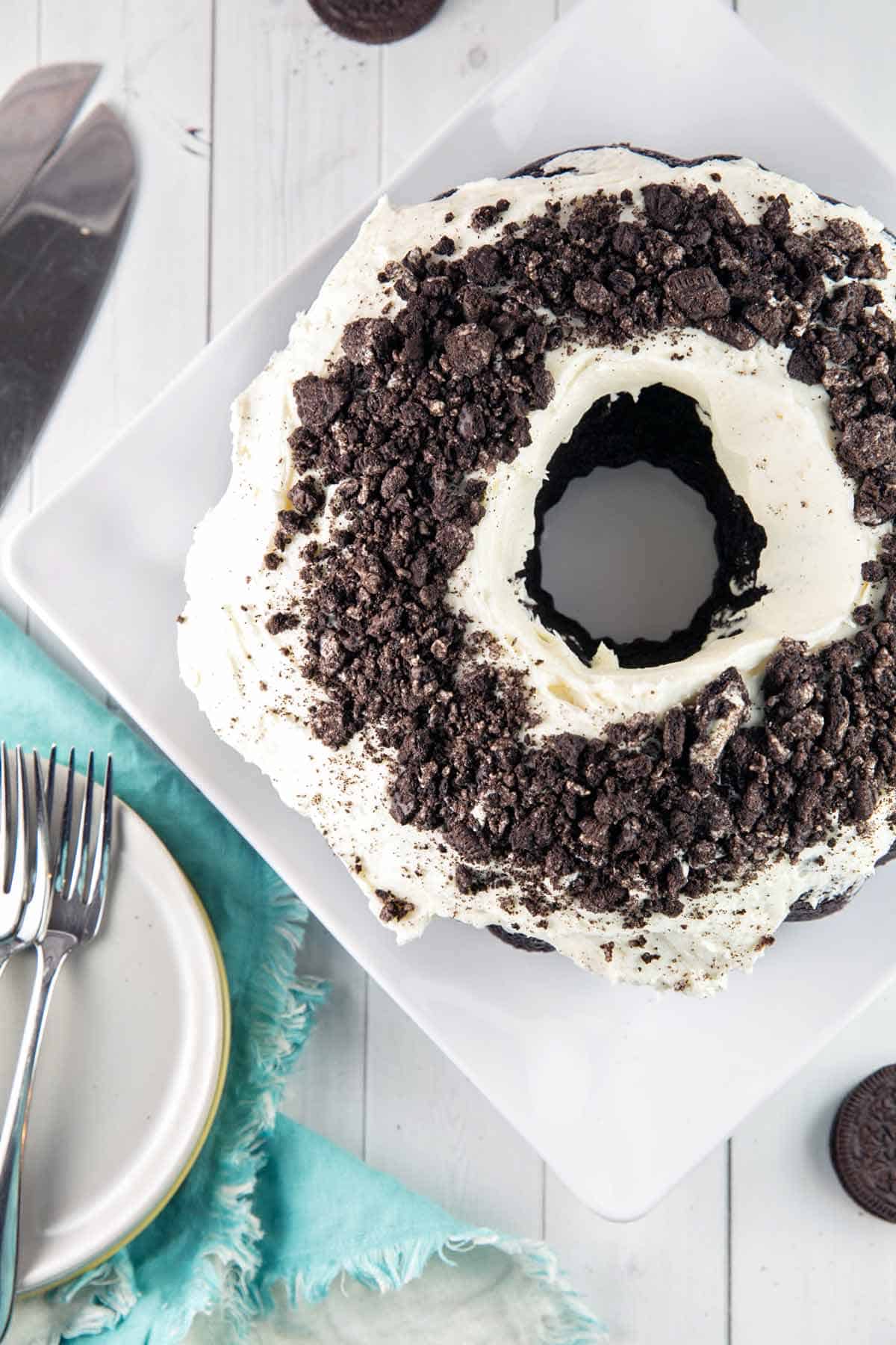 chocolate bundt cake with white frosting covered with crushed oreos
