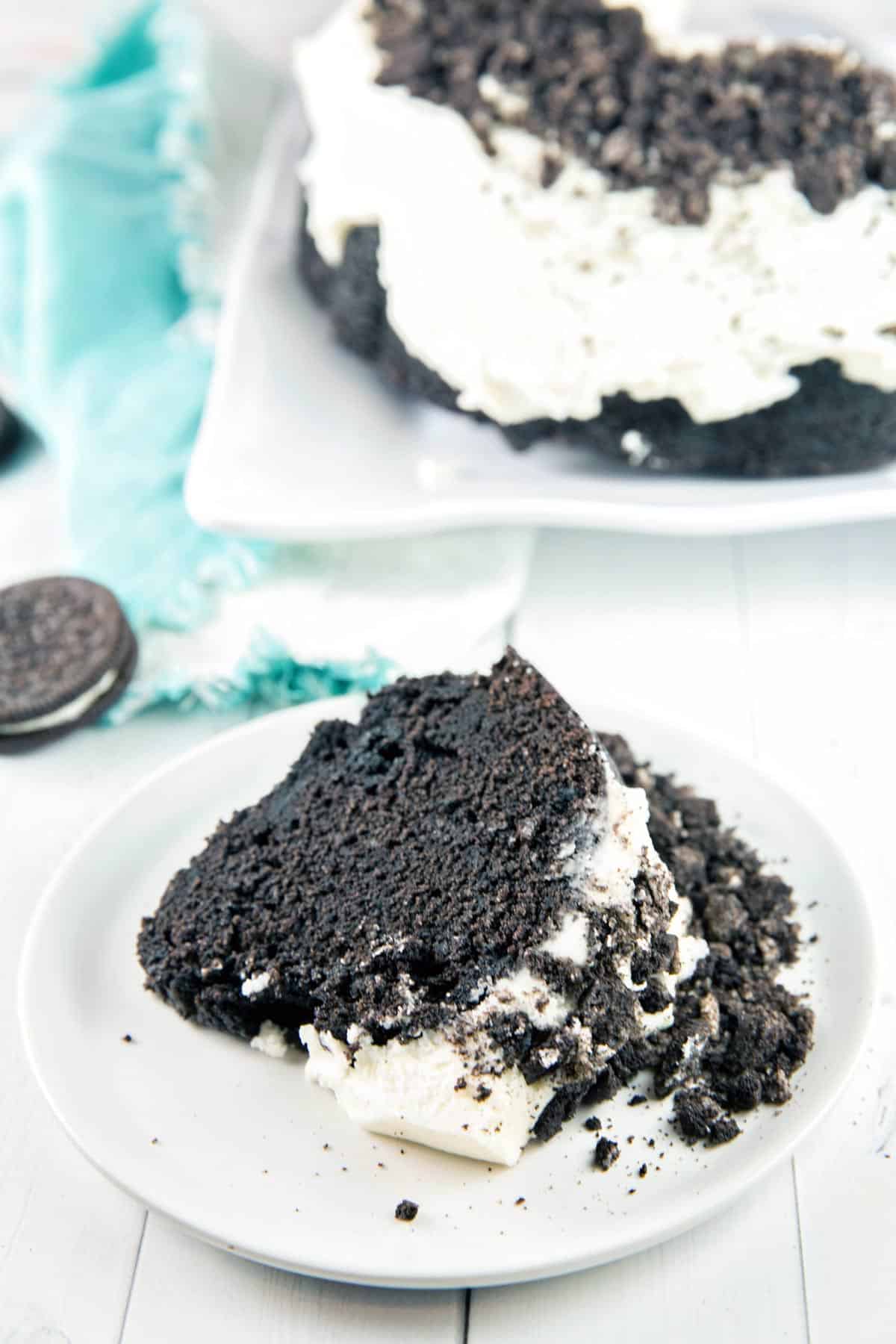 slice of oreo bundt cake on its side on a plate with blue dishcloth in background