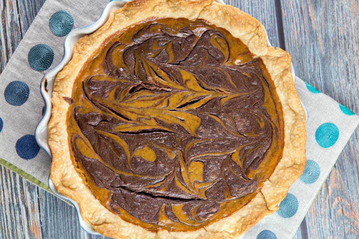 overhead image of a pumpkin pie baked with swirls of nutella