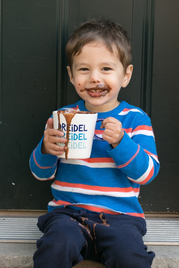 young child holding a mug of hot chocolate