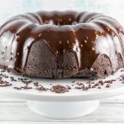 chocolate bundt cake covered with ganache glaze on a cake stand