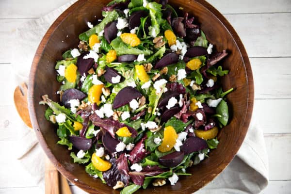 overhead view of a wooden salad bowl filled with roasted beet salad with mandarin oranges and goat cheese