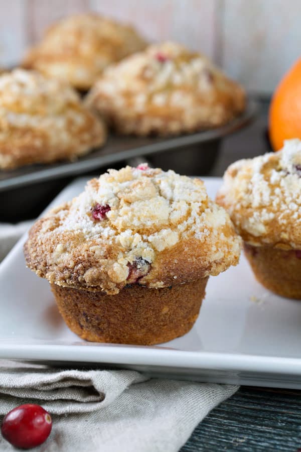 side view of freshly baked cranberry orange muffins with a streusel topping.