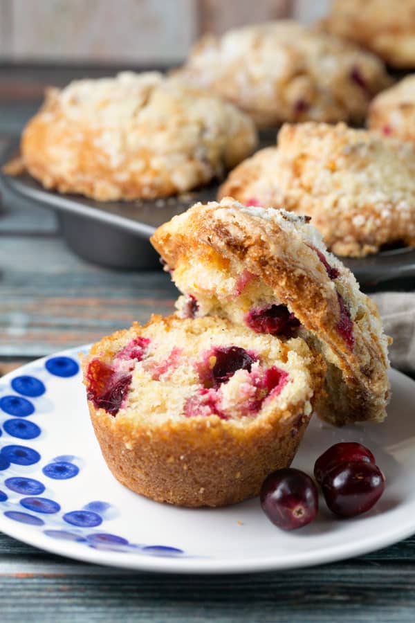 domed top of a muffin cut off to reveal large cranberries inside the baked muffin.