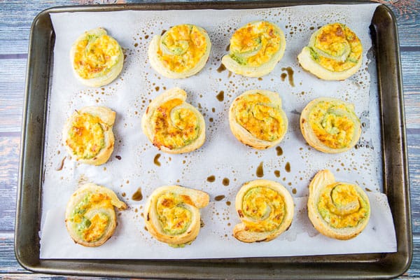 12 puff pastry pinwheels spaced out on a baking sheet.