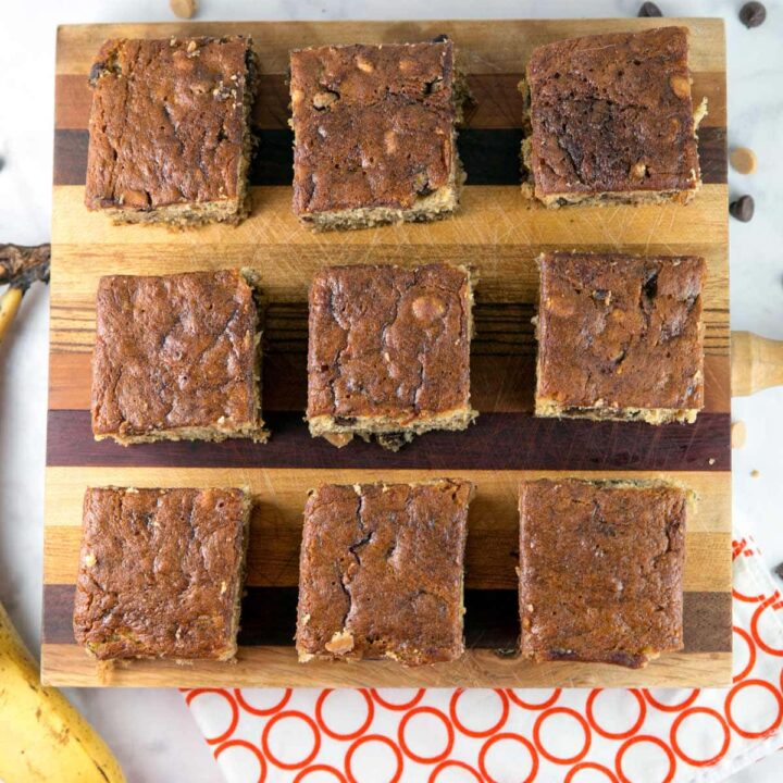 nine banana bars full of chocolate and peanut butter chips on a wooden cutting board
