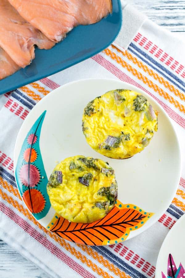 two egg muffins on a plate filled with parsley and smoked salmon.