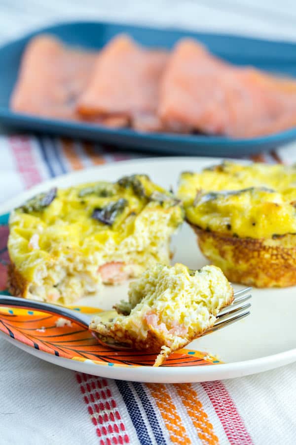 side view of an egg muffin with one forkful removed showing the smoked salmon on the inside.