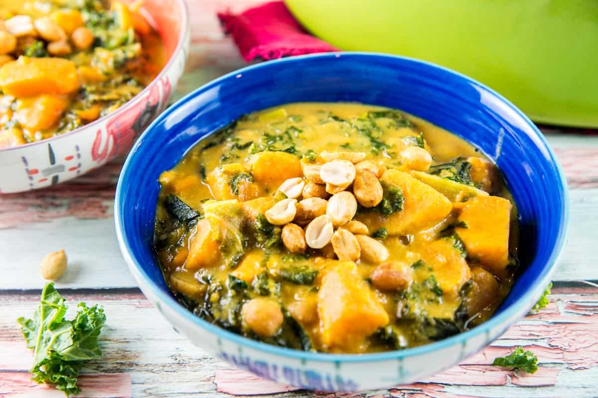 blue bowl filled with soup with chunks of sweet potatos and peanuts.