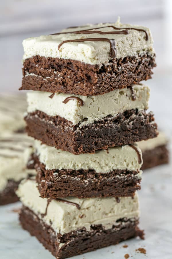 vertical stack of brownies covered with tahini buttercream frosting.