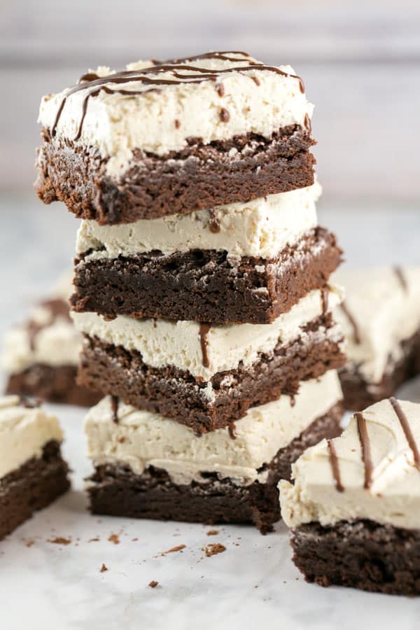 stack of tahini brownies covered with a thick fluffy layer of frosting.