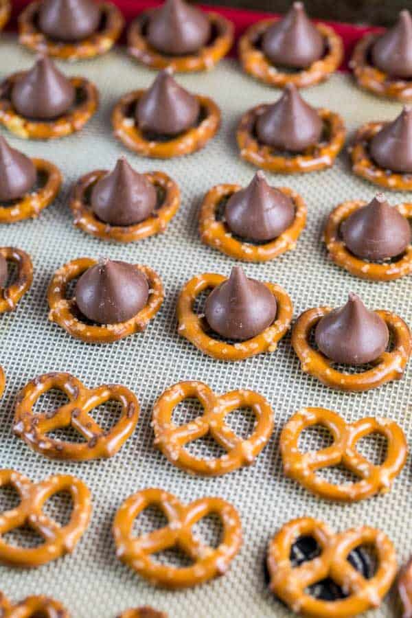 pretzels on a sheet pan with hershey kisses added in rows