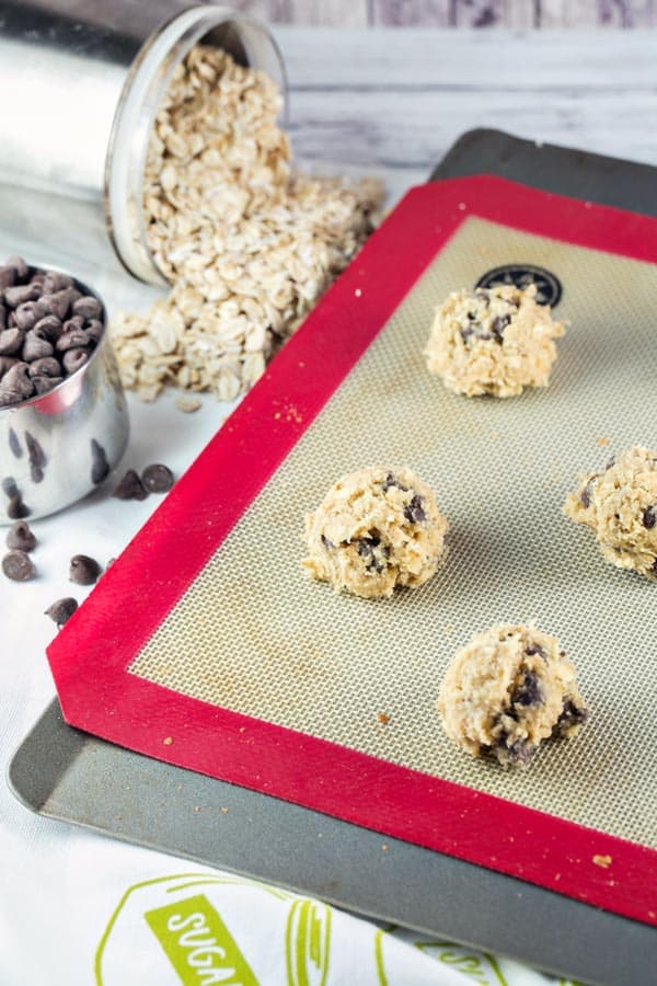 scoops of cookie dough on a silicone mat lined baking sheet.