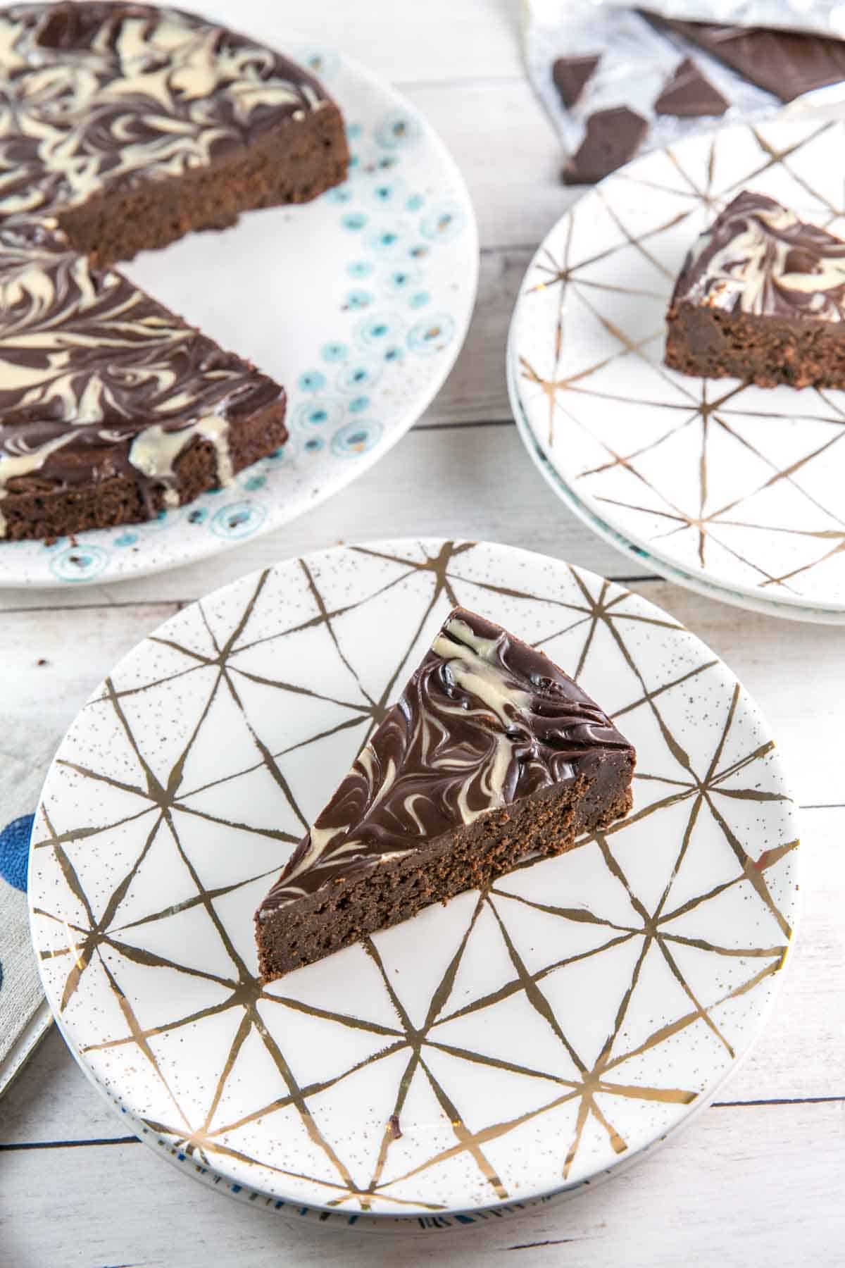 slices of flourless chocolate cake covered with swirls of tahini on decorative dessert plates