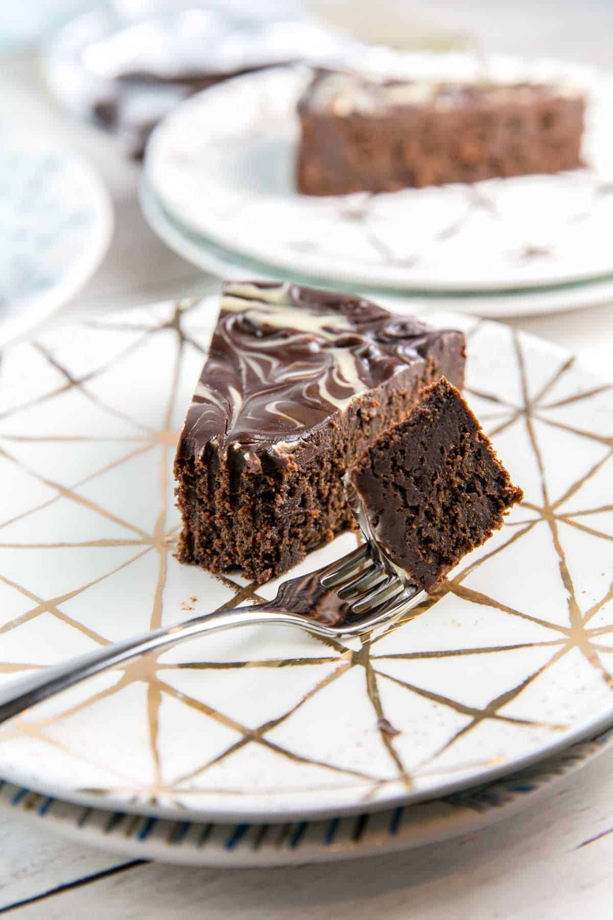 forkful of chocolate tahini cake resting on a gold dessert plate