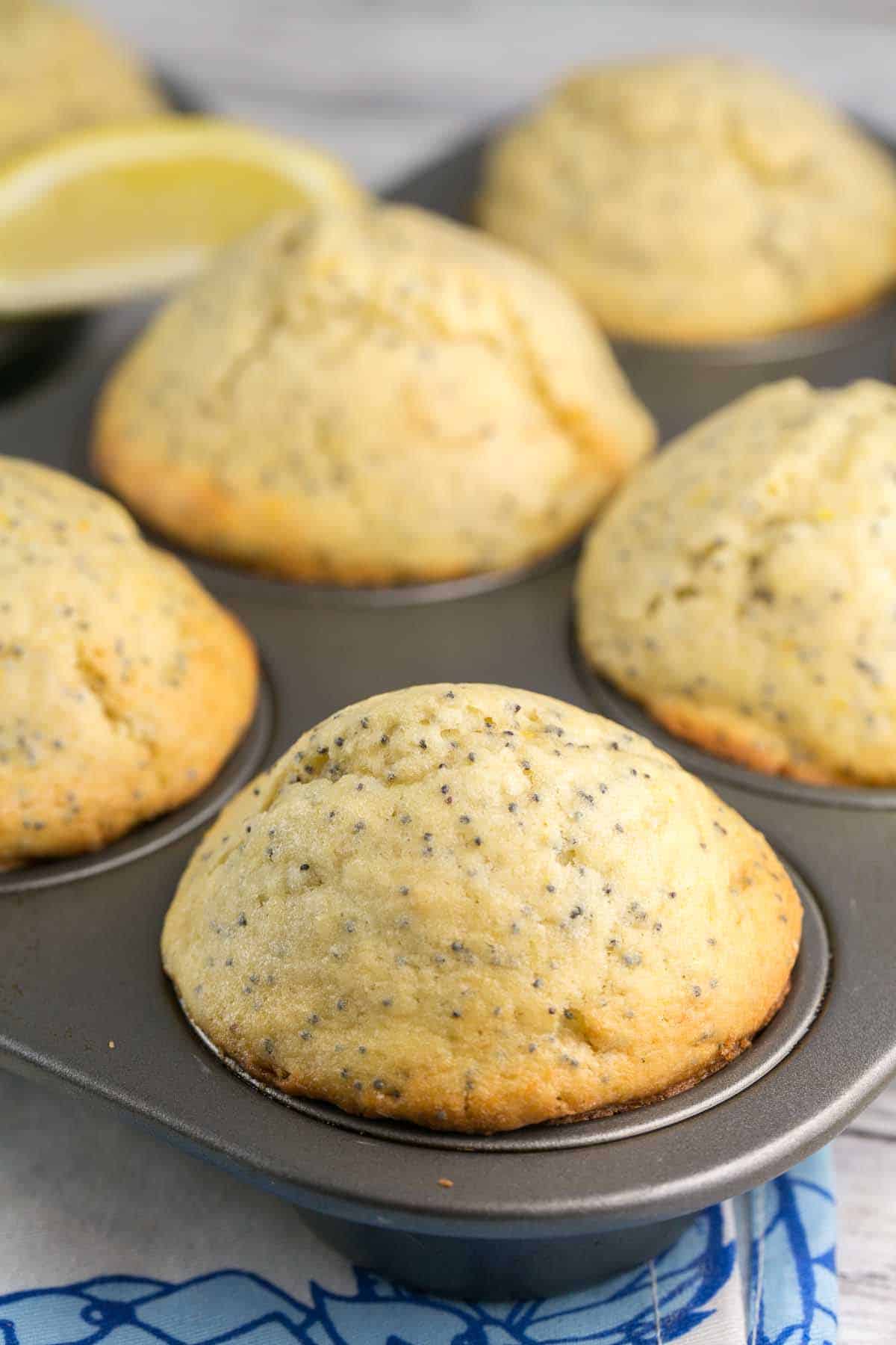 side view of domed golden yellow muffins still in the muffin tin.