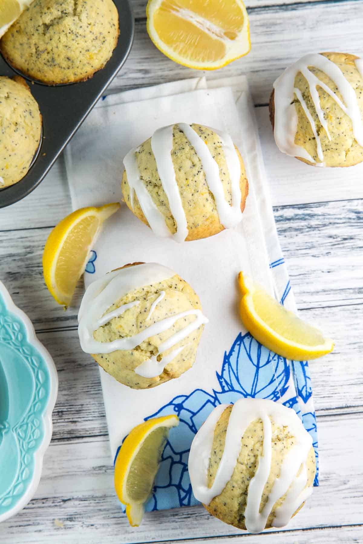 lemon poppy seed muffins covered with a thick glaze next to wedges of fresh lemon.