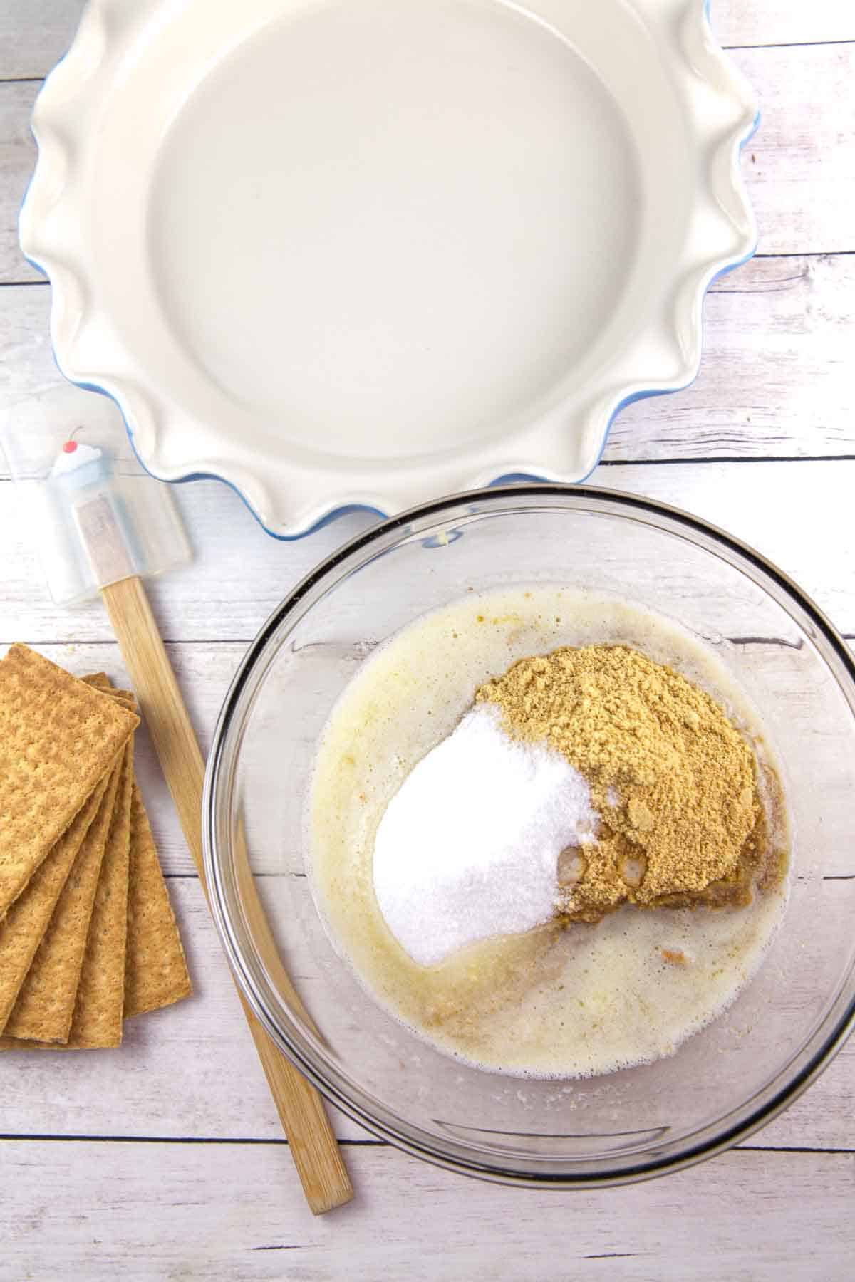 ingredients used to make a graham cracker crust in a glass mixing bowl