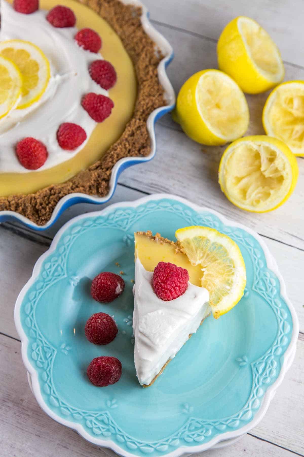 single slice of pie on a decorative blue dessert plate with whole raspberries
