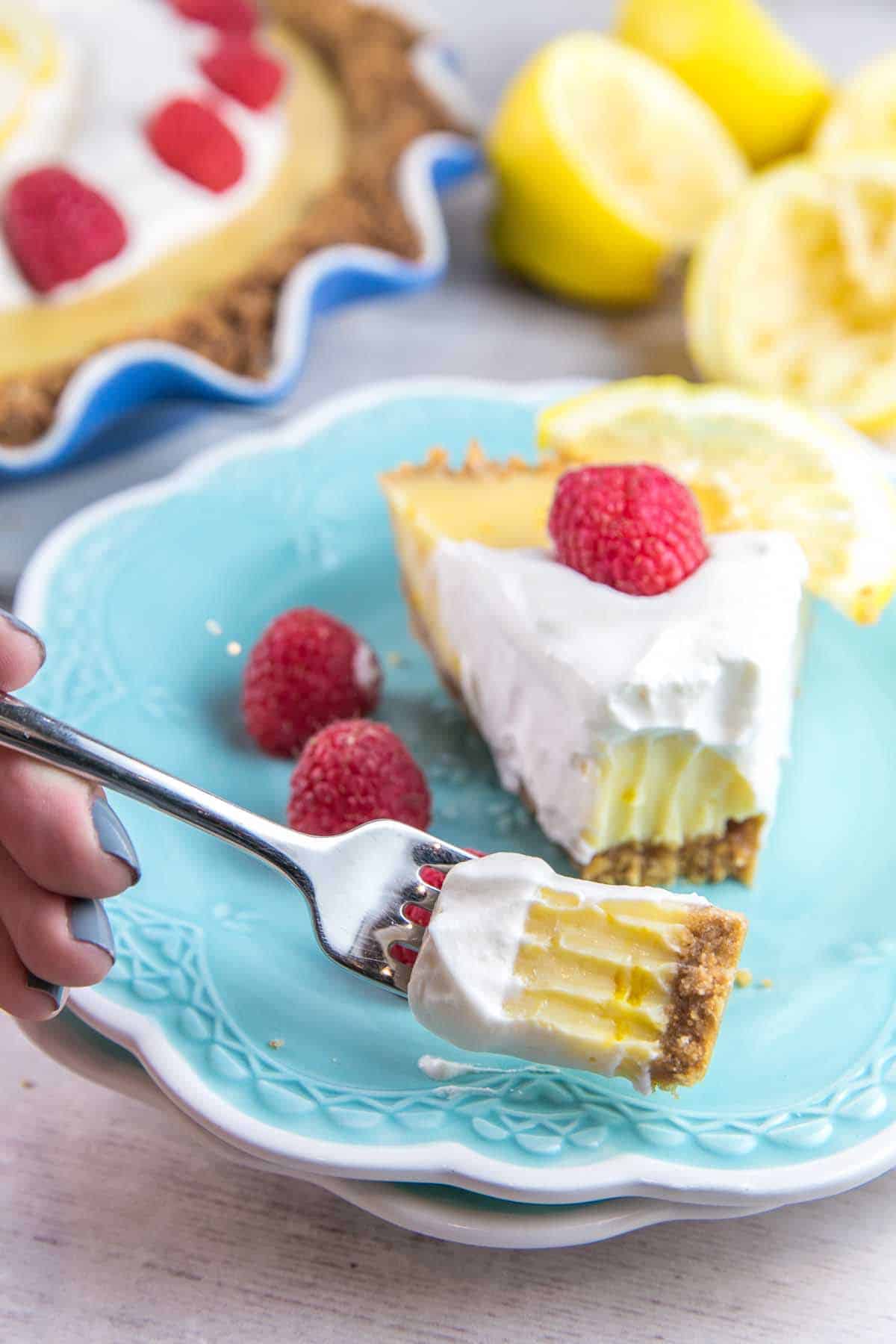  forkful of silky smooth lemon pie next to the rest of the slice of pie