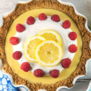 lemon pie in a graham cracker crust covered with whipped cream and raspberries