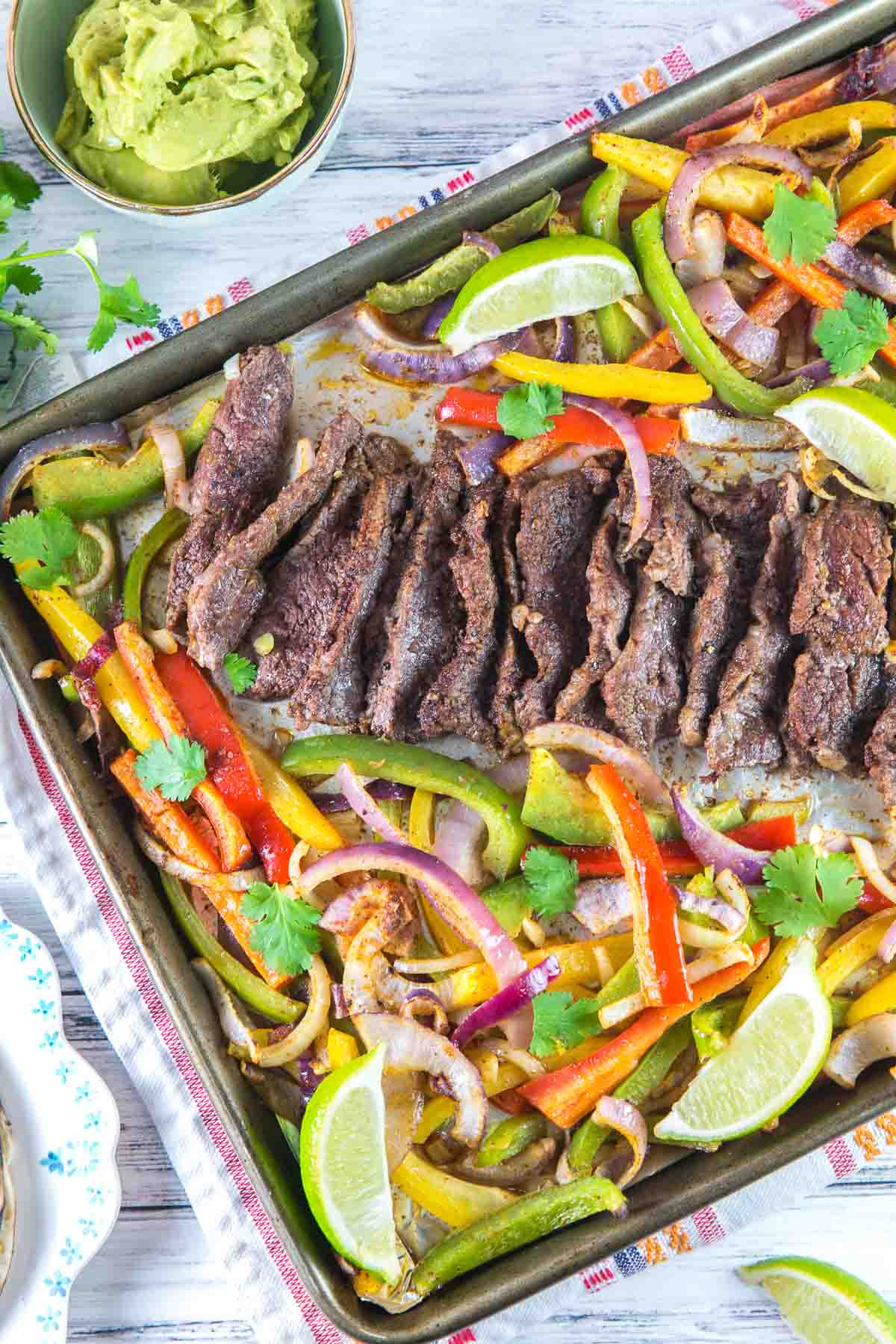 large sheet pan piled with cooked onions, peppers, and steak