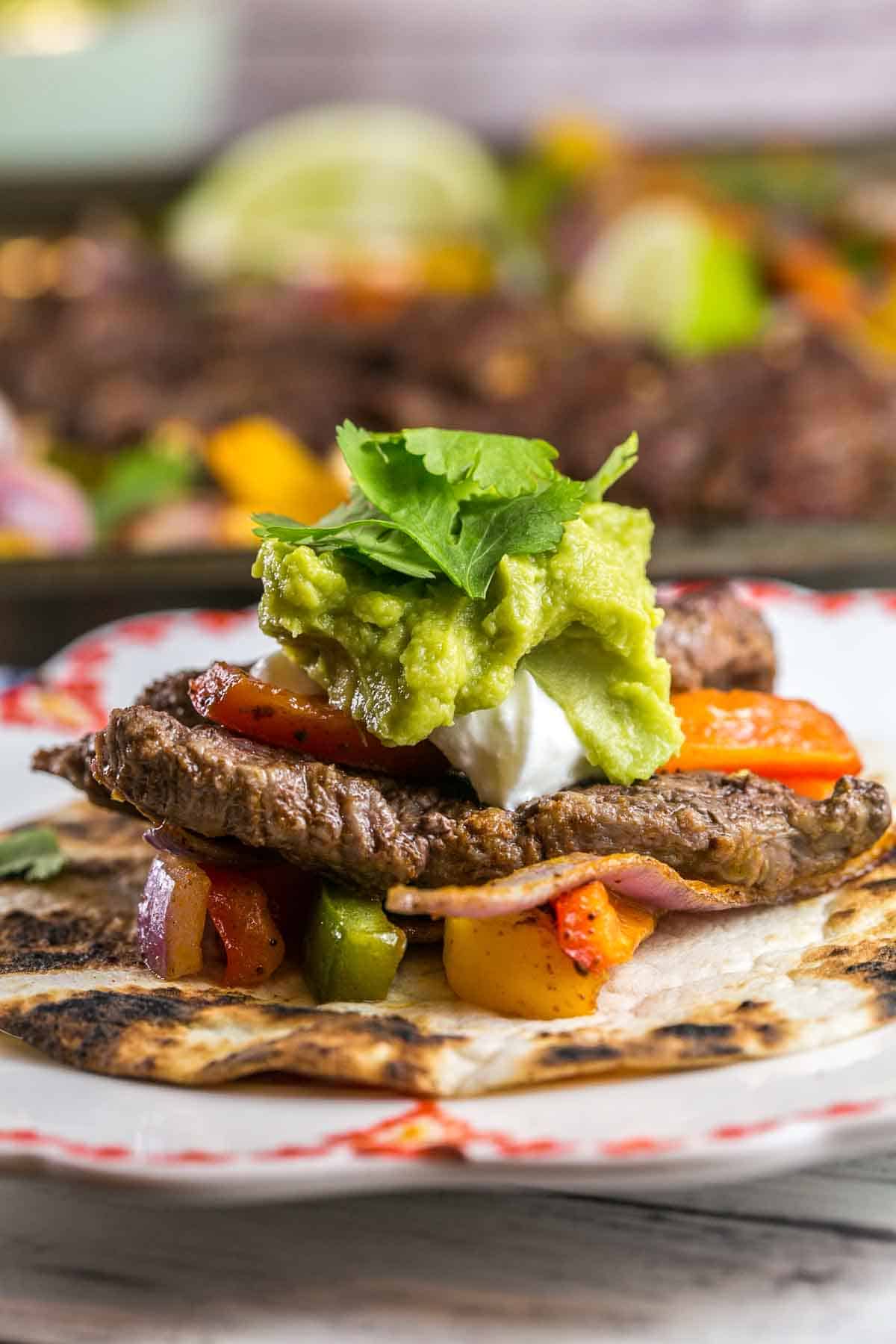 side view of a fajita piled high with sour cream and guacamole