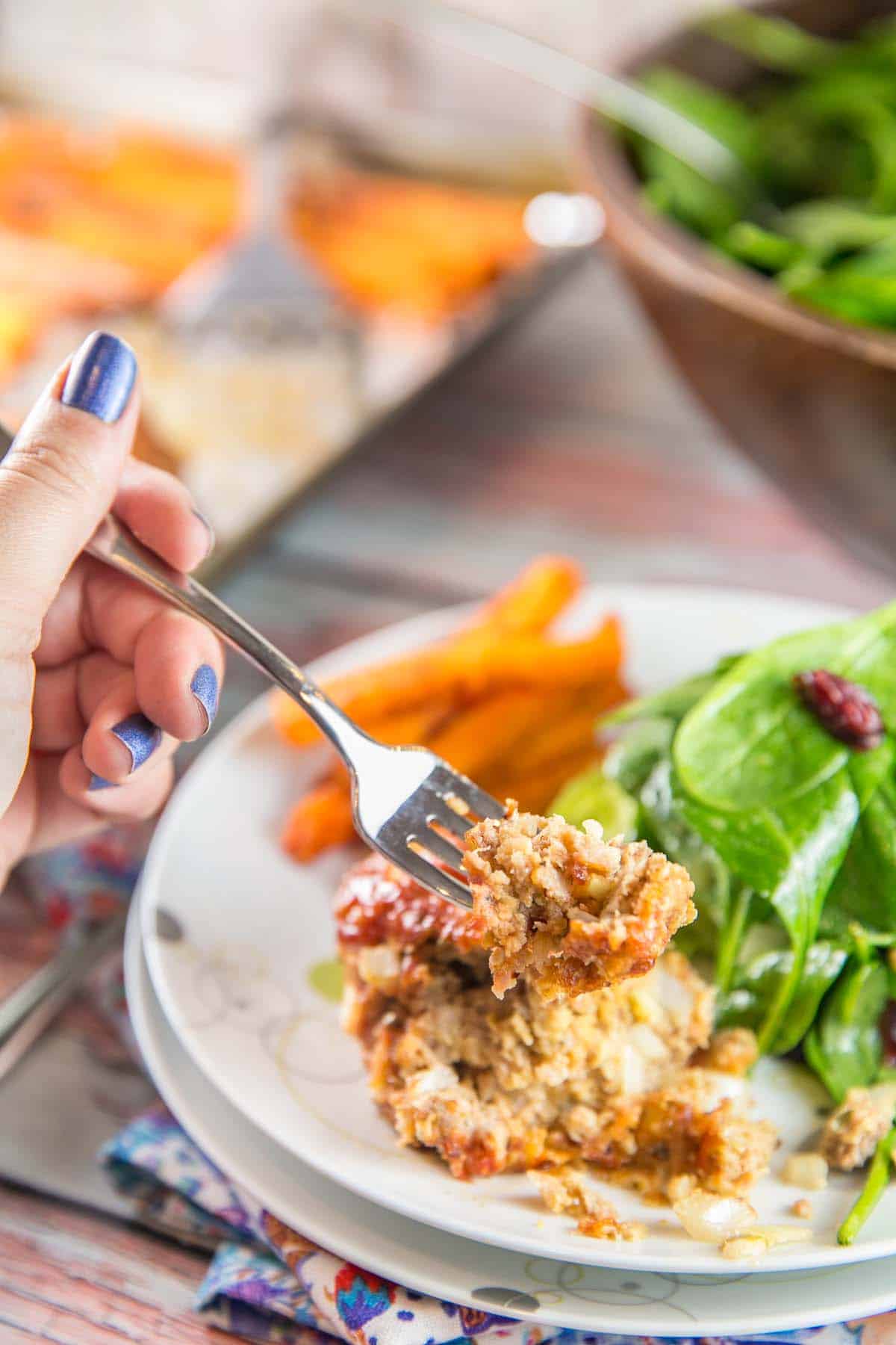 hand holding a fork scooping up a bite of meatloaf.