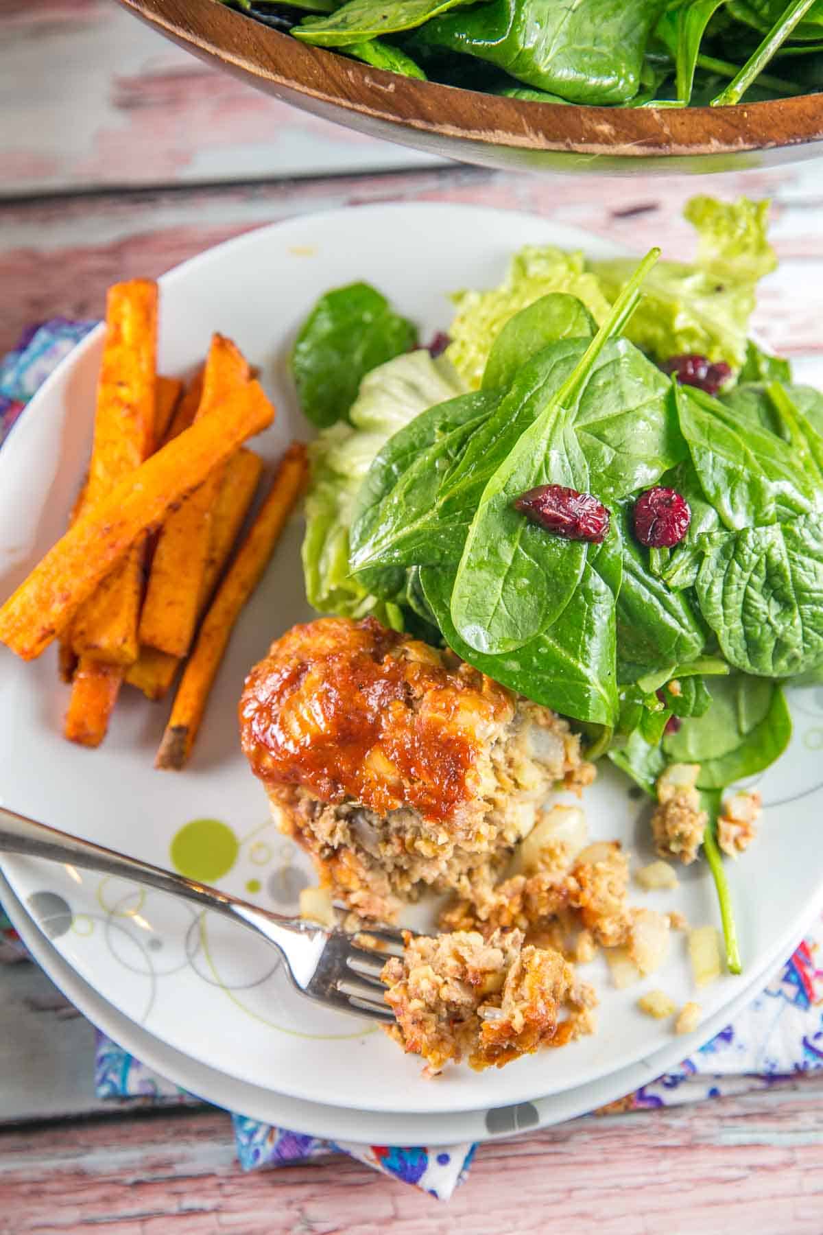 meatloaf with a forkful removed next to sweet potatoes and salad.