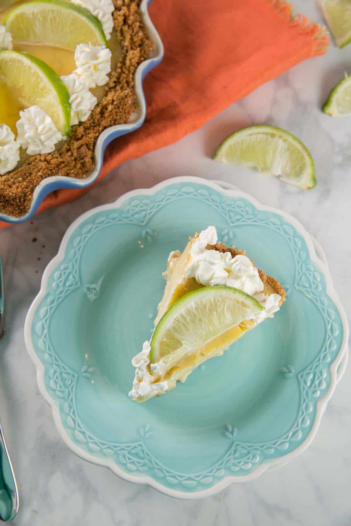 single slice of pie with a lime wedge on top on a blue dessert plate