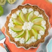 lime custard pie made with tequila in a graham cracker crust decorated with whipped cream and lime slices