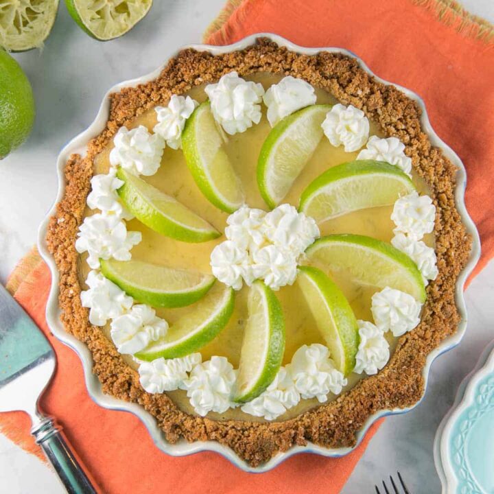 lime custard pie made with tequila in a graham cracker crust decorated with whipped cream and lime slices