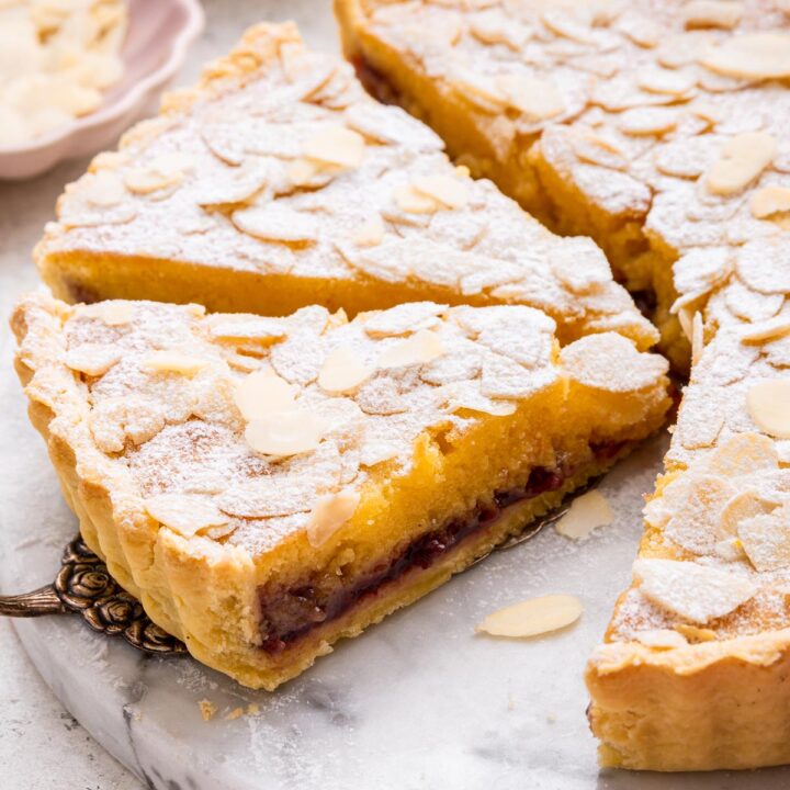 side view of a slice of bakewell tart showing the cherry jam layer inside