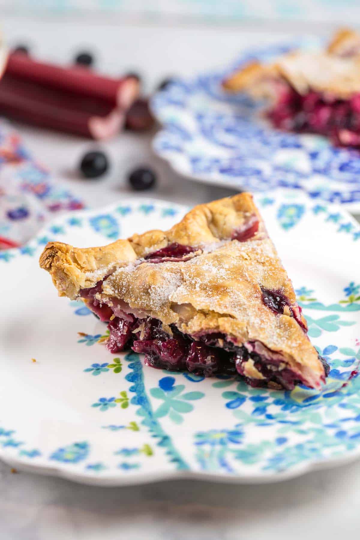 slice of blueberry rhubarb pie on a floral dessert plate