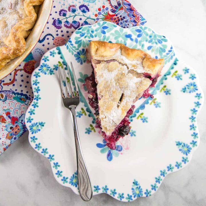 a slice of blueberry rhubarb pie on a floral dessert plate