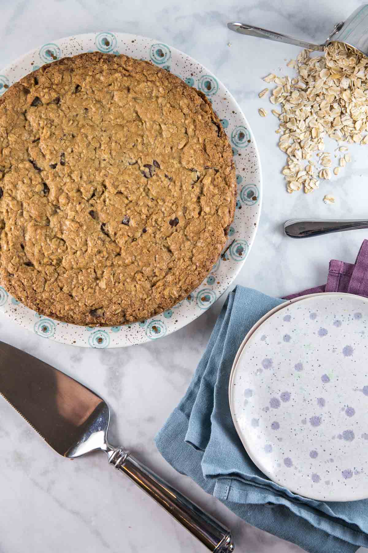overhead view of a cookie cake next to a pile of old fashioned oats 