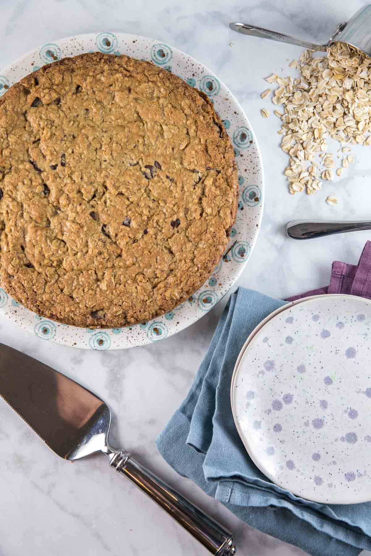 overhead view of a cookie cake next to a pile of old fashioned oats